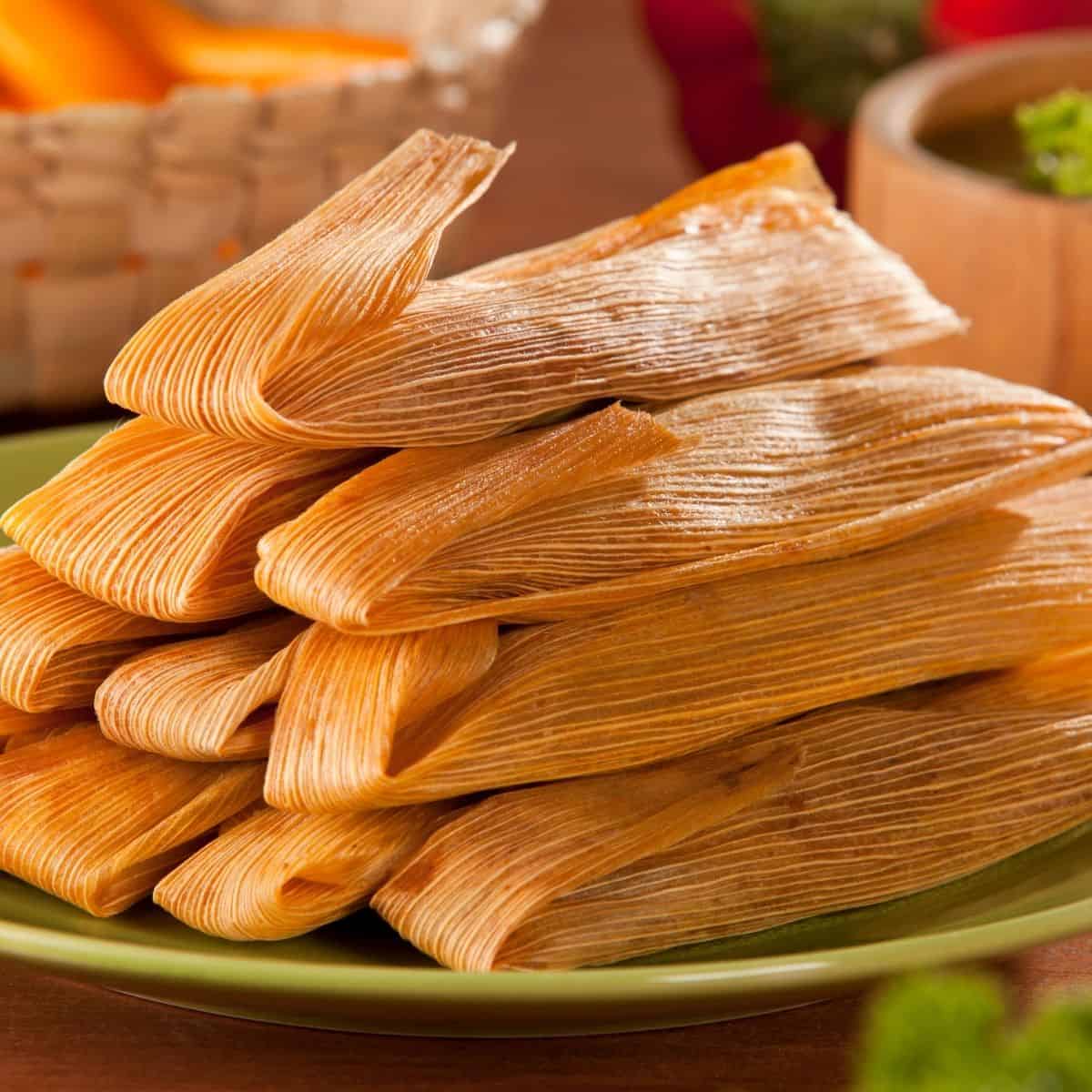 a stack of tamales wrapped in corn husks on a plate